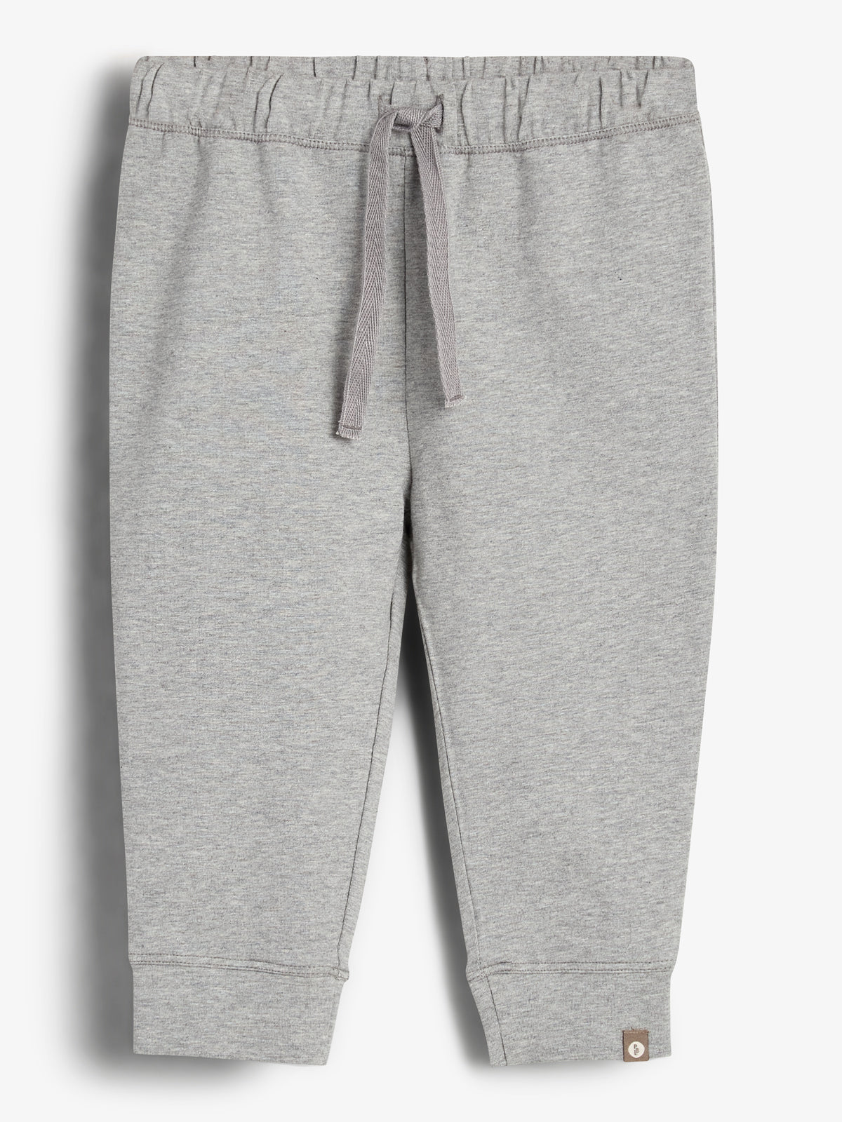 Grå joggingbukser med snoretræk i taljen, placeret mod en hvid baggrund. Bukserne har elastik ved anklerne og en lille mærkat nær bunden.