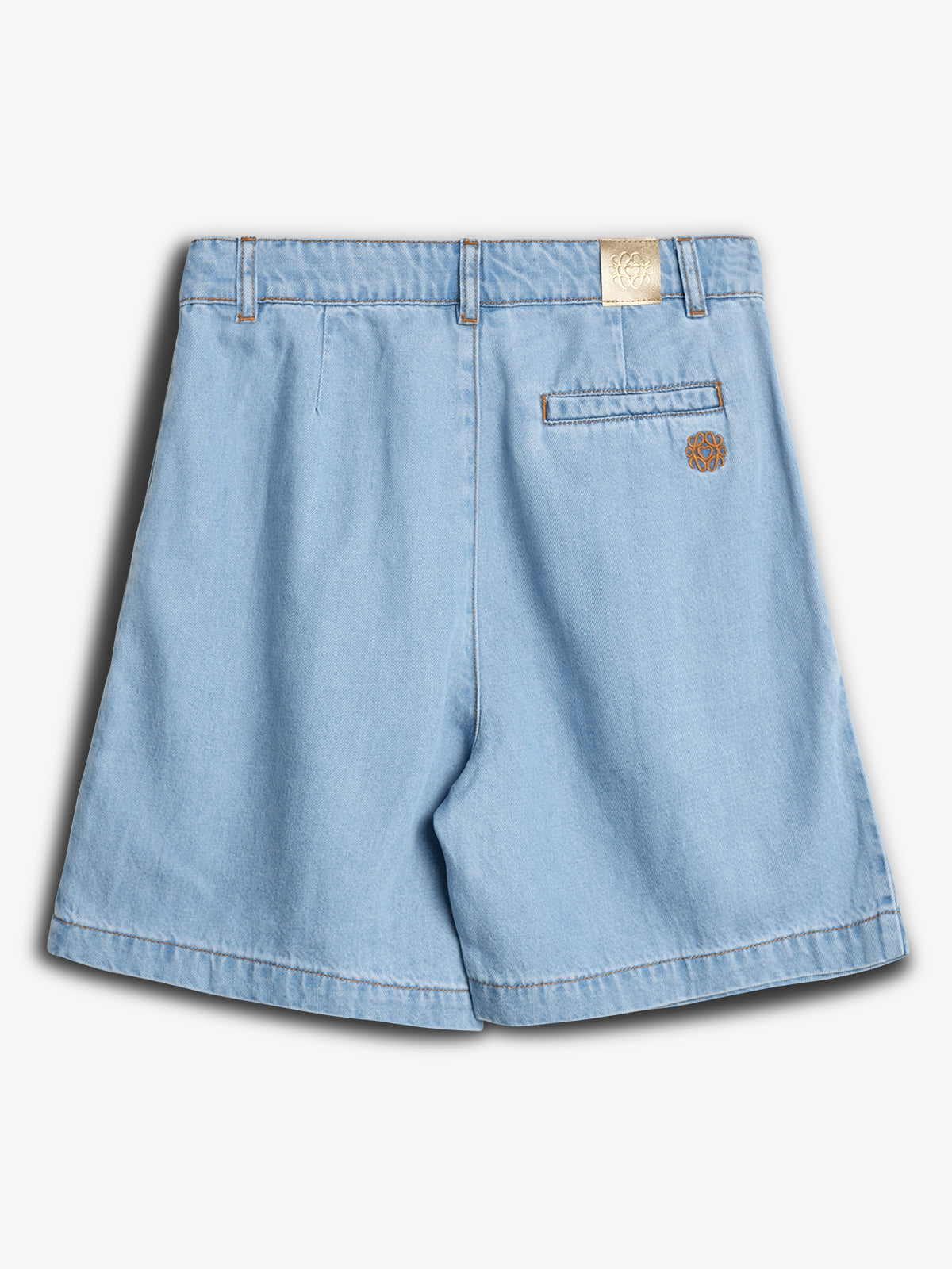 Blå denimshorts ligger fladt, set bagfra. En lomme med et brunt logo og et beige mærke ved linningen. Kortene er på en hvid baggrund.