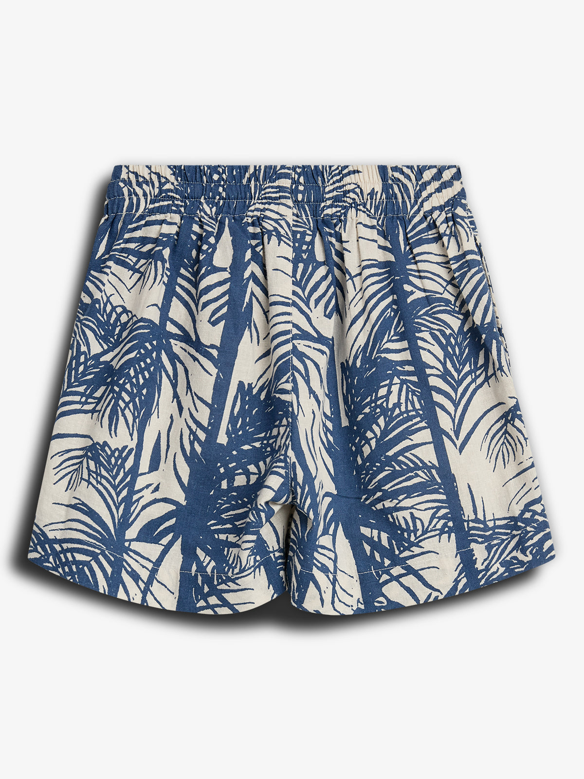 Shorts med blå palmemønster på hvid baggrund. De har en elastisk talje og er placeret mod en ensfarvet hvid baggrund.