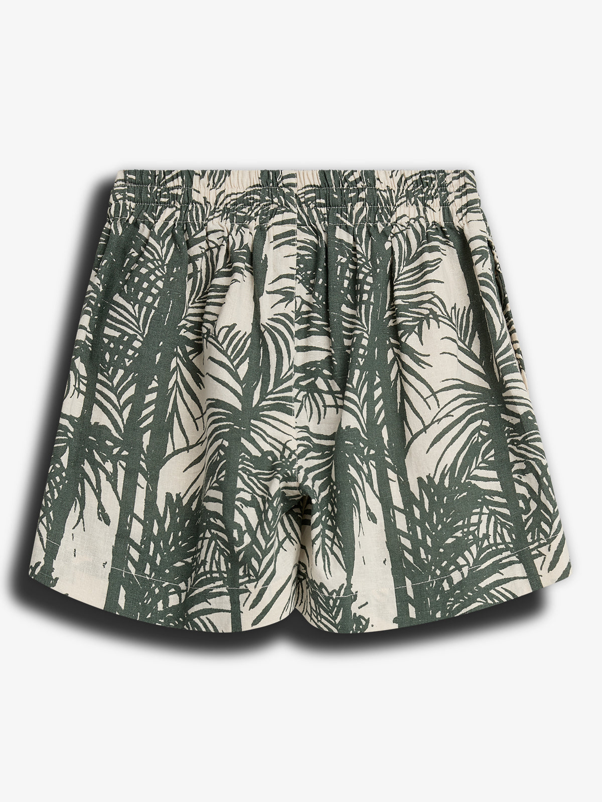 Shorts med elastisk talje, dekoreret med et grønt palmebladsmønster mod en lys baggrund. Baggrunden er ensfarvet og fokuserer på mønsterdetaljerne.