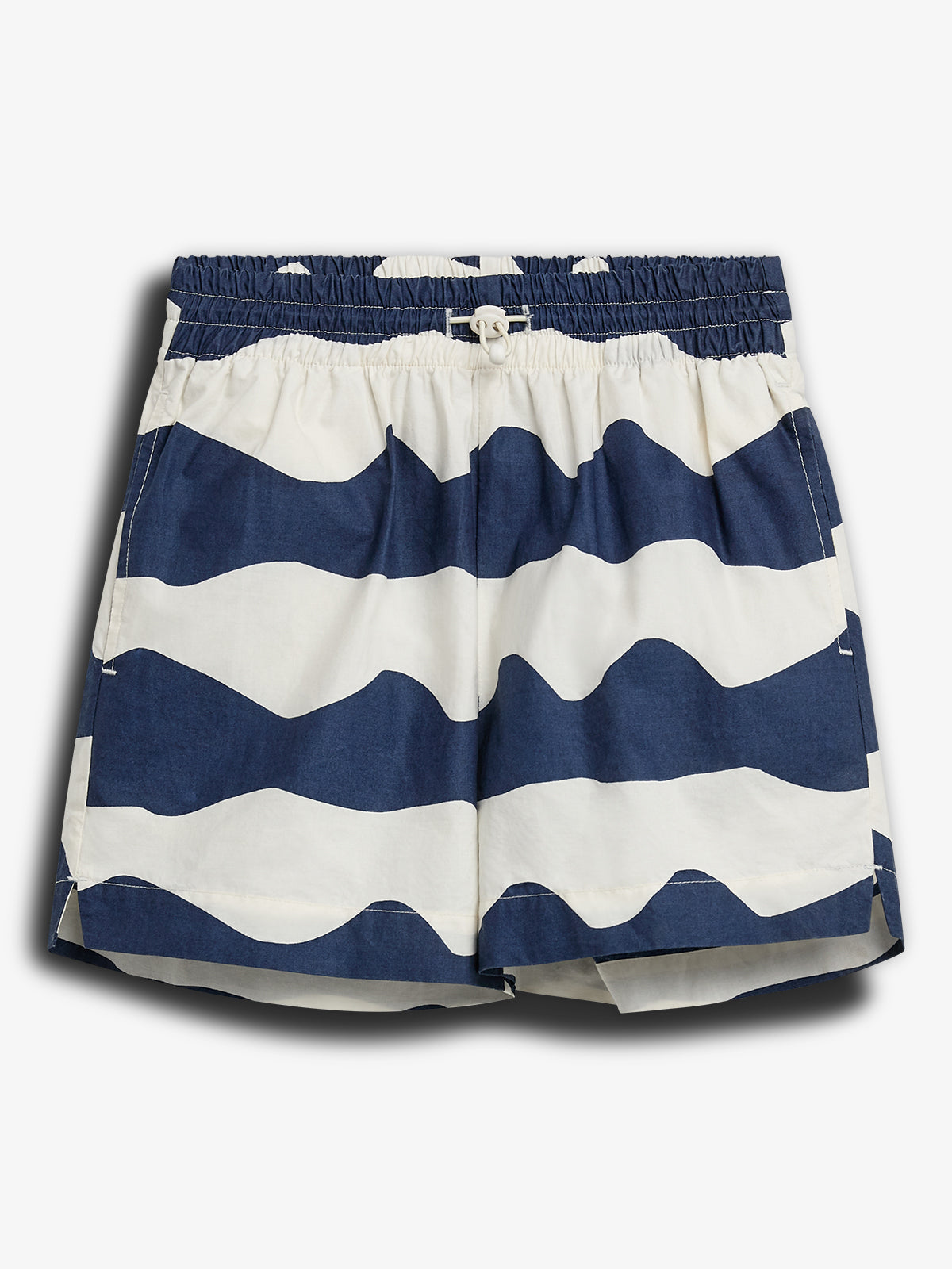 Shorts med maritime blåt-hvidt bølgemønster. Elastisk talje med justérbar snor. Baggrunden er neutral og lysegrå, hvilket fremhæver tøjets detaljer og farver.