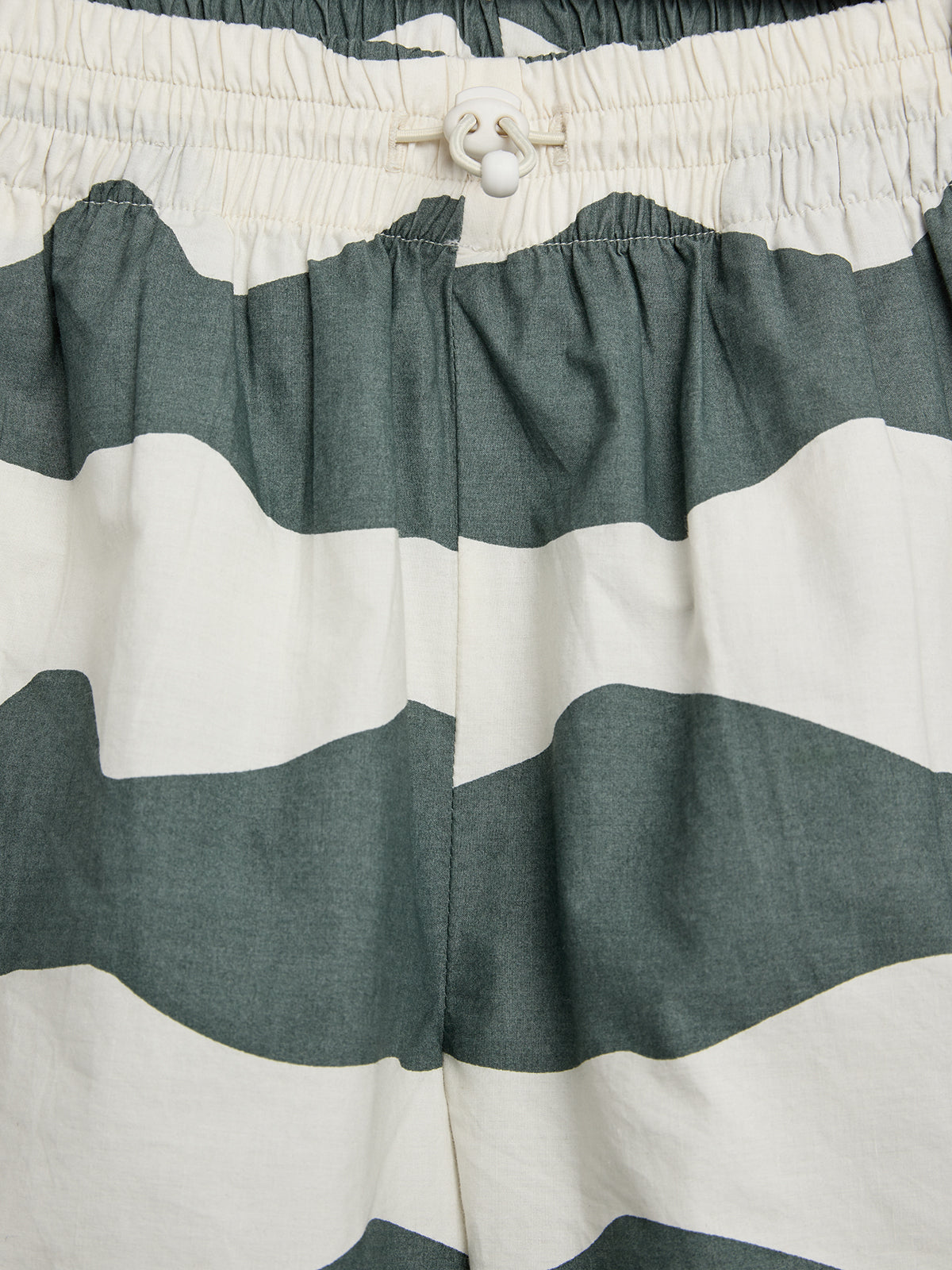 Shorts med brede sorte og hvide vandrette striber. De har en elastisk talje med en justerbar snor. Stoffet har et afslappet draperi.