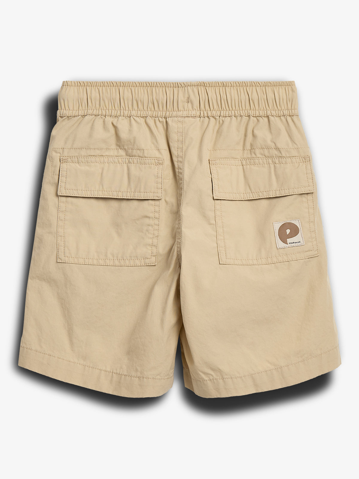Beige shorts med elastisk talje, placeret med bagsiden opad, har to baglommer. En patch med et logo er påsyet den ene lomme. Baggrunden er hvid.