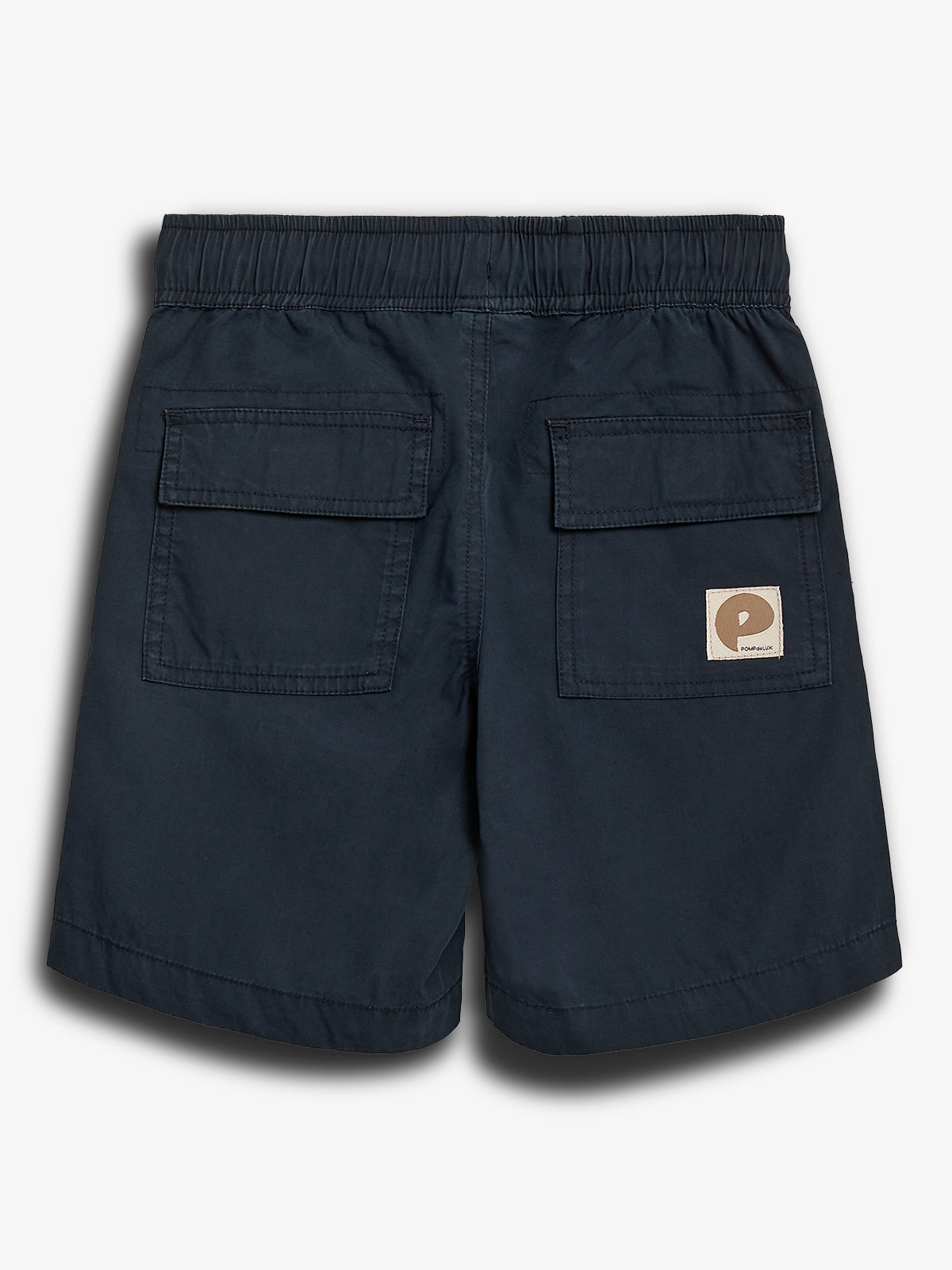 Mørkeblå shorts med elastisk talje og to baglommer med klap. Et firkantet, brunt mærke med et bogstav "P" er syet på den ene lomme. Neutral baggrund.