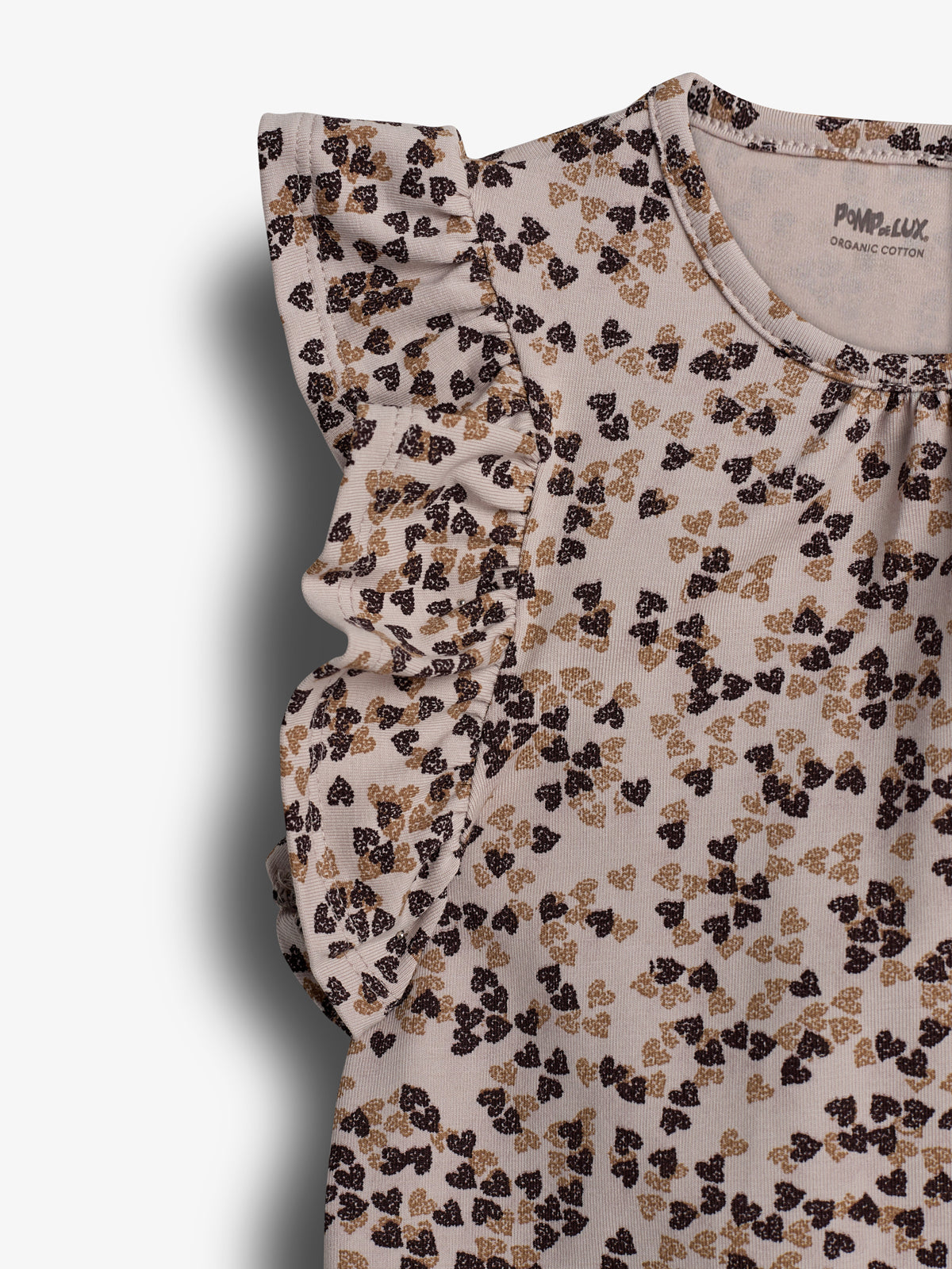 Bluse med flæseærmer, dekoreret med brune og sorte blomstermønstre, hænger mod en hvid baggrund. Tekst på mærket: "POMPdeLUX ORGANIC COTTON".