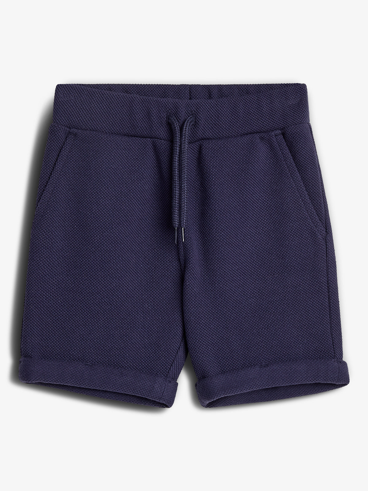 Mørkeblå shorts med snøre i taljen, sidelommer, og opsmøgede kanter, ligger på en hvid baggrund.