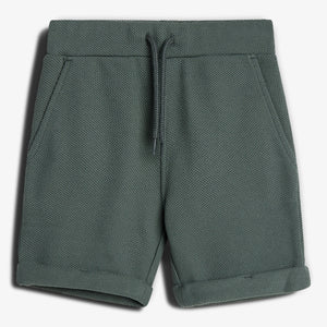 Grønne shorts med snøre i taljen, liggende fladt mod en hvid baggrund. Stoffet har en tekstureret overflade. Ingen tekst ses på billedet.