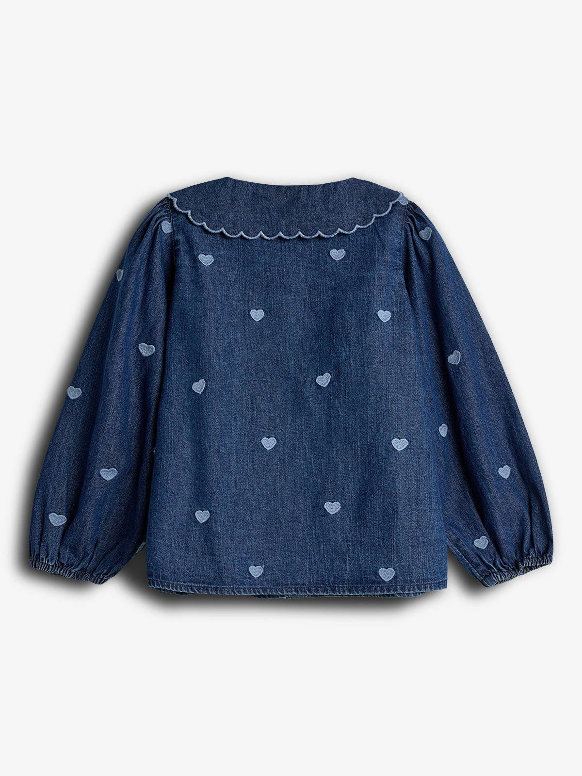 Blå denimbluse med lange ærmer, dekoreret med hjertebroderi. Blusens krave har en bølget kant. Ingen tekst i billedet. Hvid baggrund.