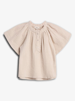 A cream-colored, short-sleeved baby blouse hangs in a white background. The blouse features a gathered neckline, button closure, and loose, textured fabric, creating a casual and comfortable look.