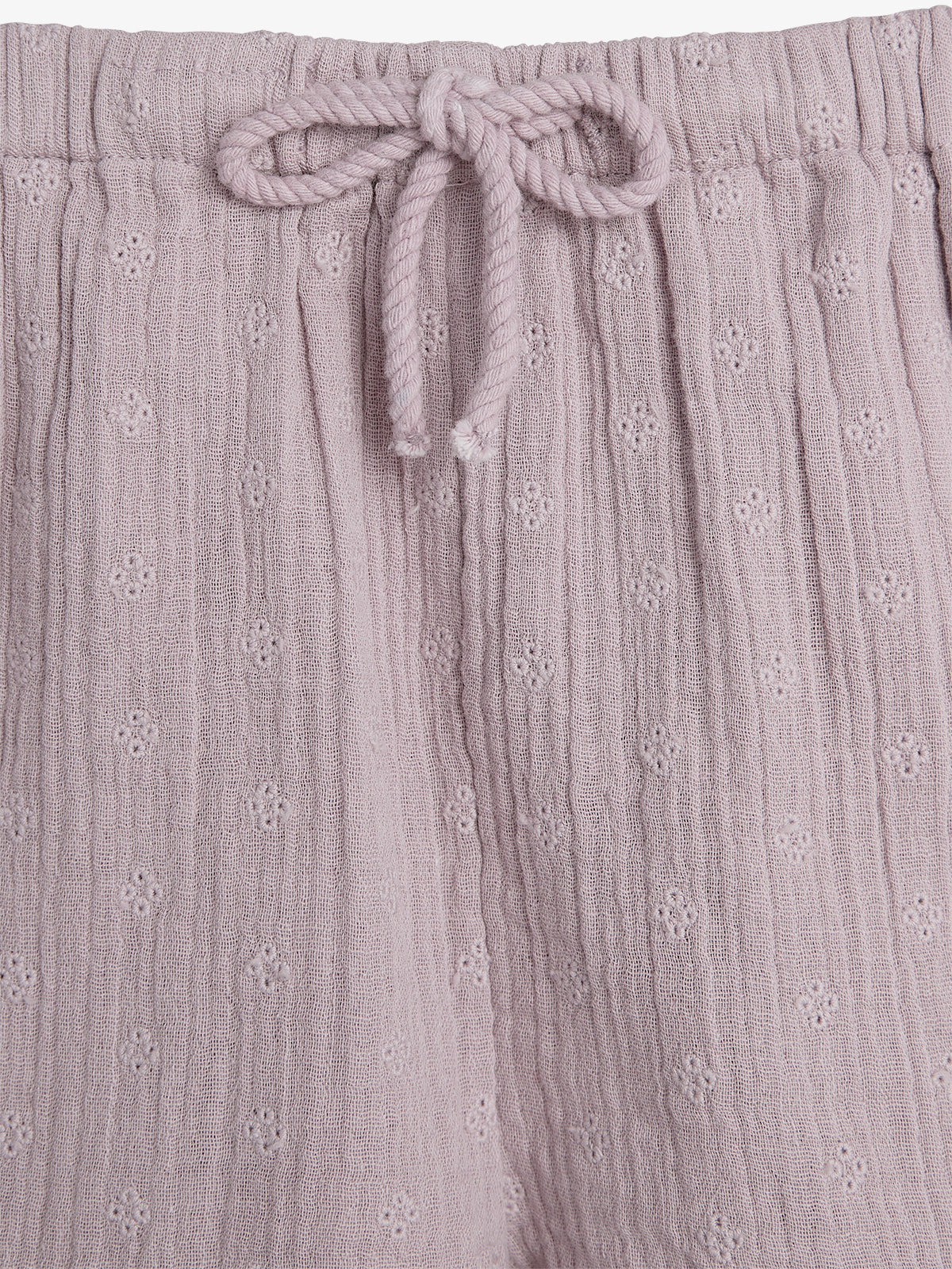Purple textured fabric forms the focus, featuring a drawstring closure with a bow. The material displays a subtle floral pattern in a close-up view.