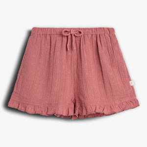 Pink shorts featuring a drawstring waistband and ruffled hem; small embroidered patterns adorn the fabric, adding texture. Displayed against a white background.