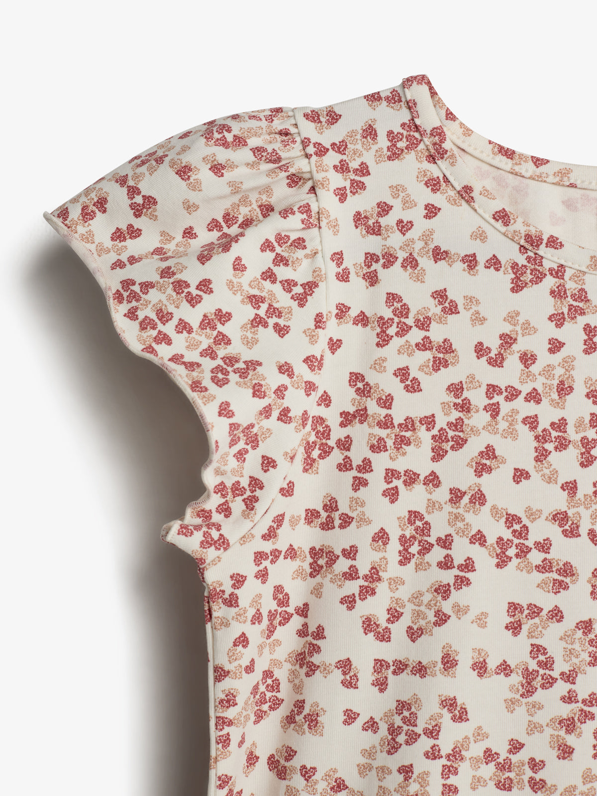 Bluse med kortærmer dekoreret med små, røde blomsterprint. Stoffet er lyst og blødt, skaber et delikat og feminint udtryk i en minimalistisk stil.