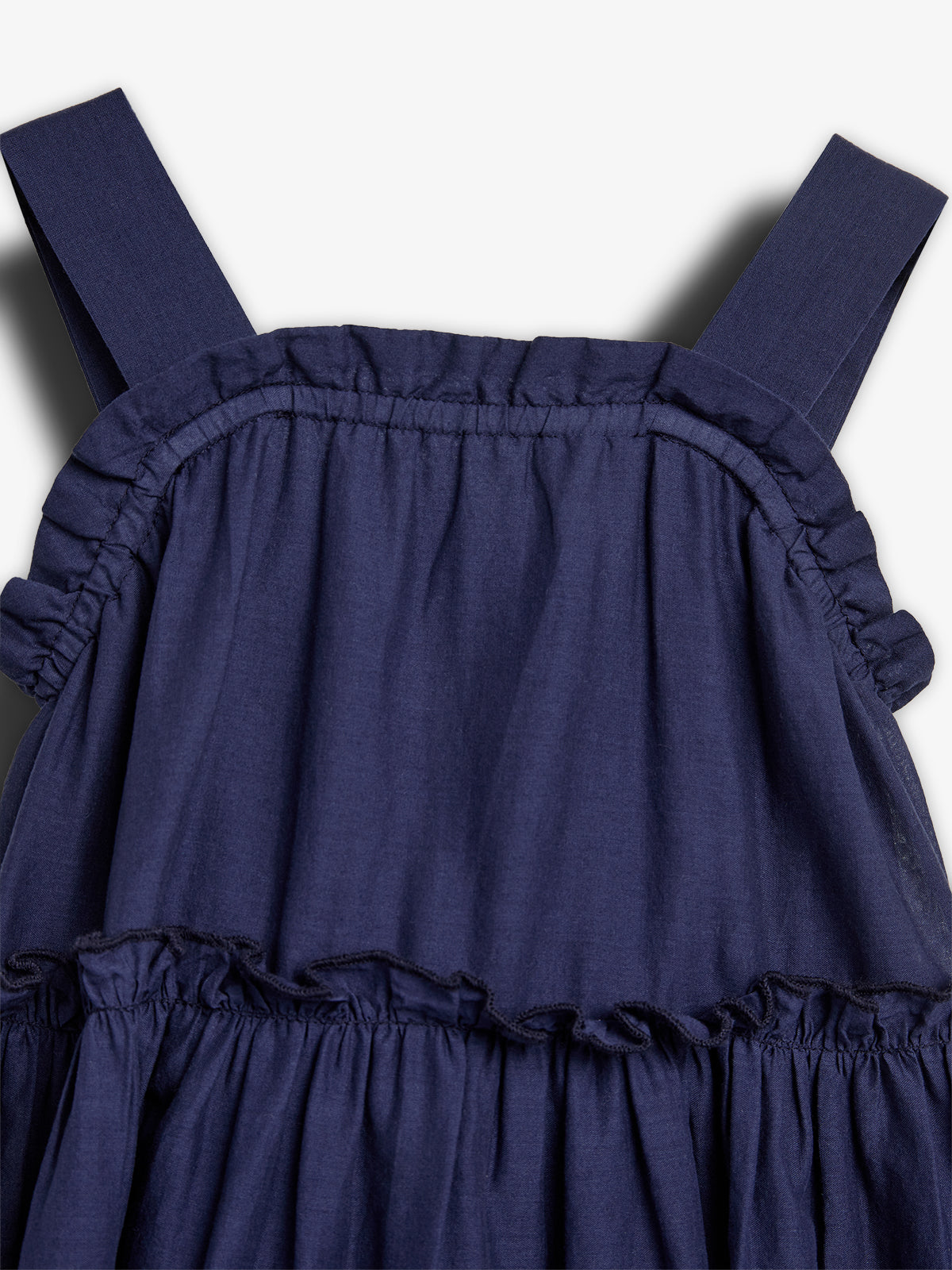 A navy blue dress with ruffled details on the bodice and straps, set against a plain, light background.