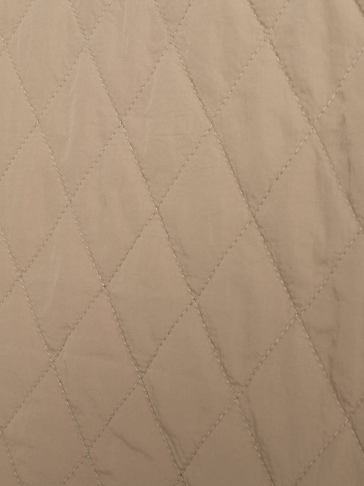 Brune, quiltede stofruder danner et diamantmønster gennem syede, parallelle tråde. Stoffet ligger fladt, uden fold eller krøller, og dækker hele billedets overflade.