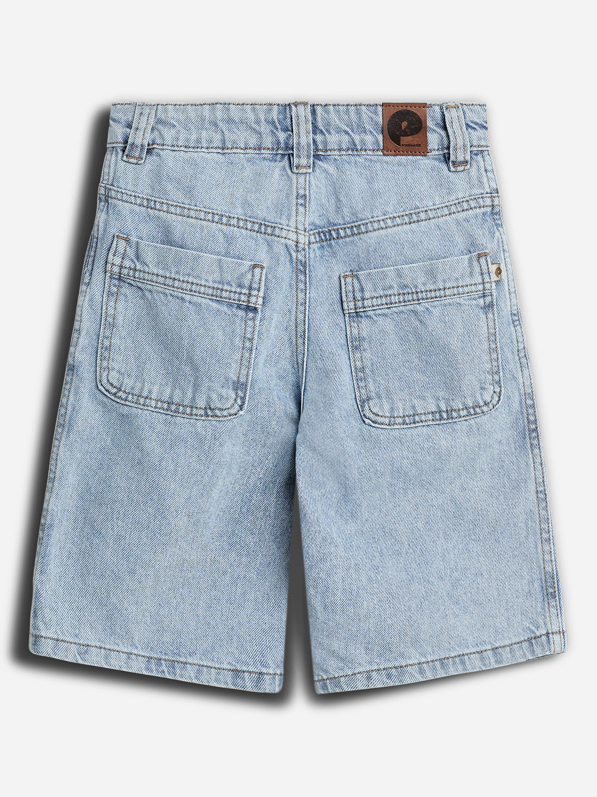 Kort denimshorts med to firkantede baglommer, bæltestropper og en brun lædermærkat. Mærkatet viser en sort halvmåneformet logo og teksten "PConsent". Baggrunden er neutral grå.