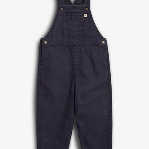 Mørkeblå overall i denim-stil, ligger fladt på en hvid baggrund. Designet har et brystlomme og justerbare skulderstropper med metalspænder, velegnet til afslappet brug.