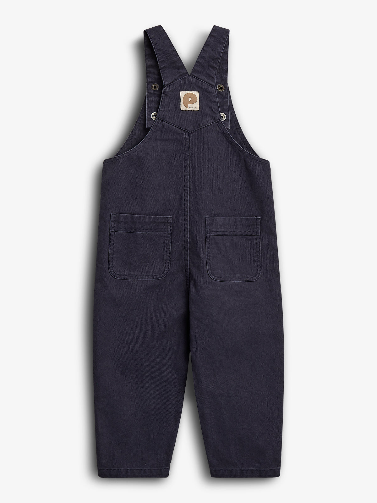 Mørkeblå overalls med to firkantede lommer foran og krydsede skulderstropper. Der er en firkantet mærkat med et logo på brystet. Baggrunden er hvid.