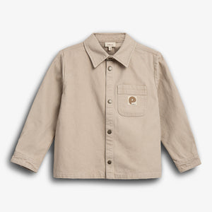 Beige skjorte med krave og knaplukning, viser en brystlomme med et lille "P" logo. Skjorten ligger fladt mod en hvid baggrund.