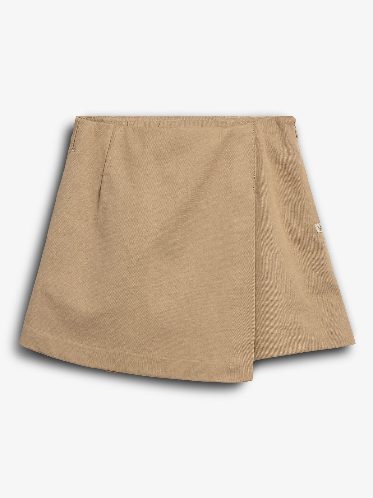 Beige nederdel ligger fladt; har en omslagsstil og elastisk talje. Et lille mærke ses på siden. Baggrunden er ensfarvet hvid.