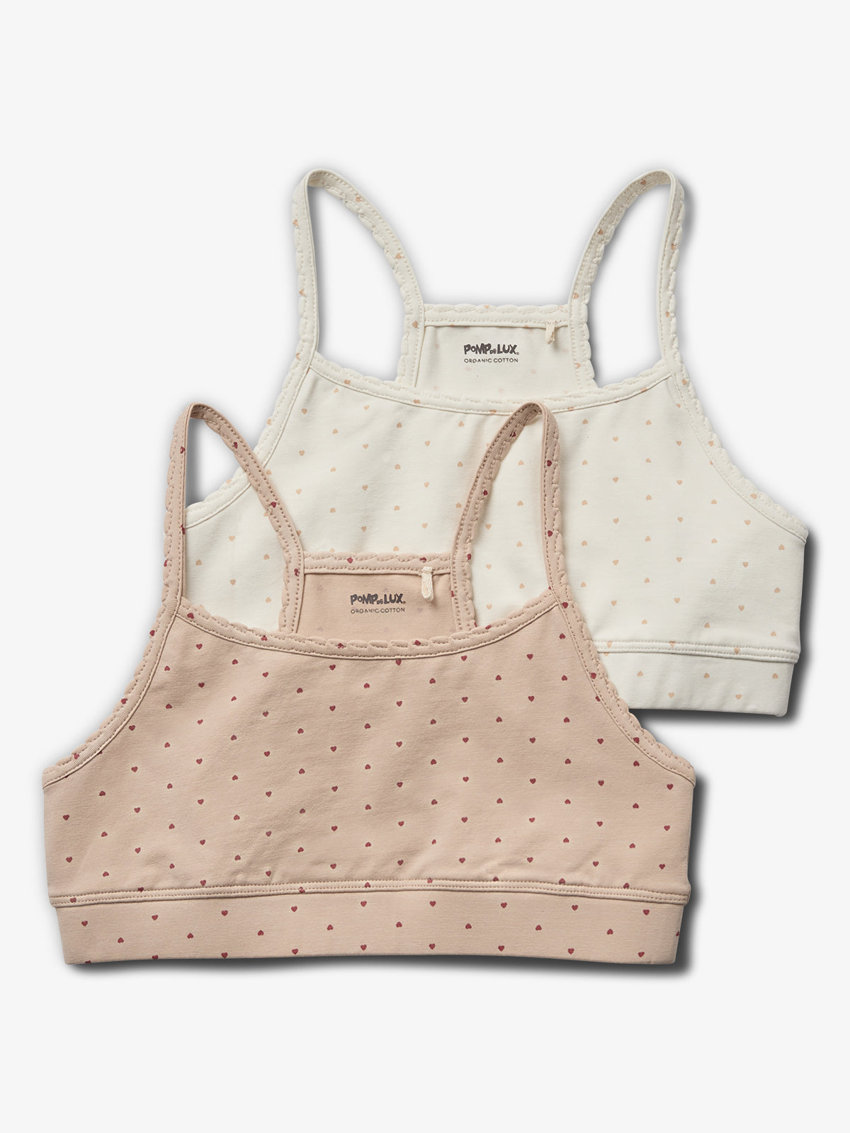 To sportsbras i blød bomuld med stropper og små hjerteprint, ligger overlappende. Tekst på indersiden: "POMPdeLUX ORGANIC COTTON". Baggrunden er ensfarvet hvid.