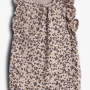 Romper med blomsterprint; har flæseærmer og trykknapper ved bunden. Baggrund i beige toner dekoreret med brune og sorte små blomster. Tekst: "PYMPLELUX ORGANIC COTTON."