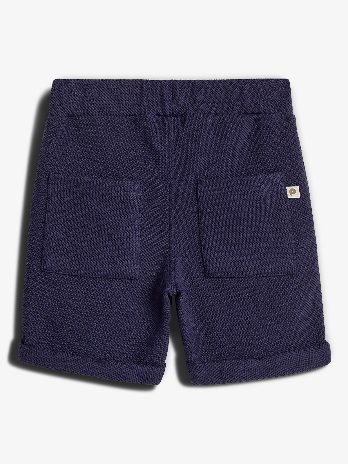 Korte, marineblå shorts med elastisk talje. De har to baglommer og opsmøgede bukseben. I en indendørs kontekst vises de mod en neutral, hvid baggrund. Et lille mærke ses på højre lomme.