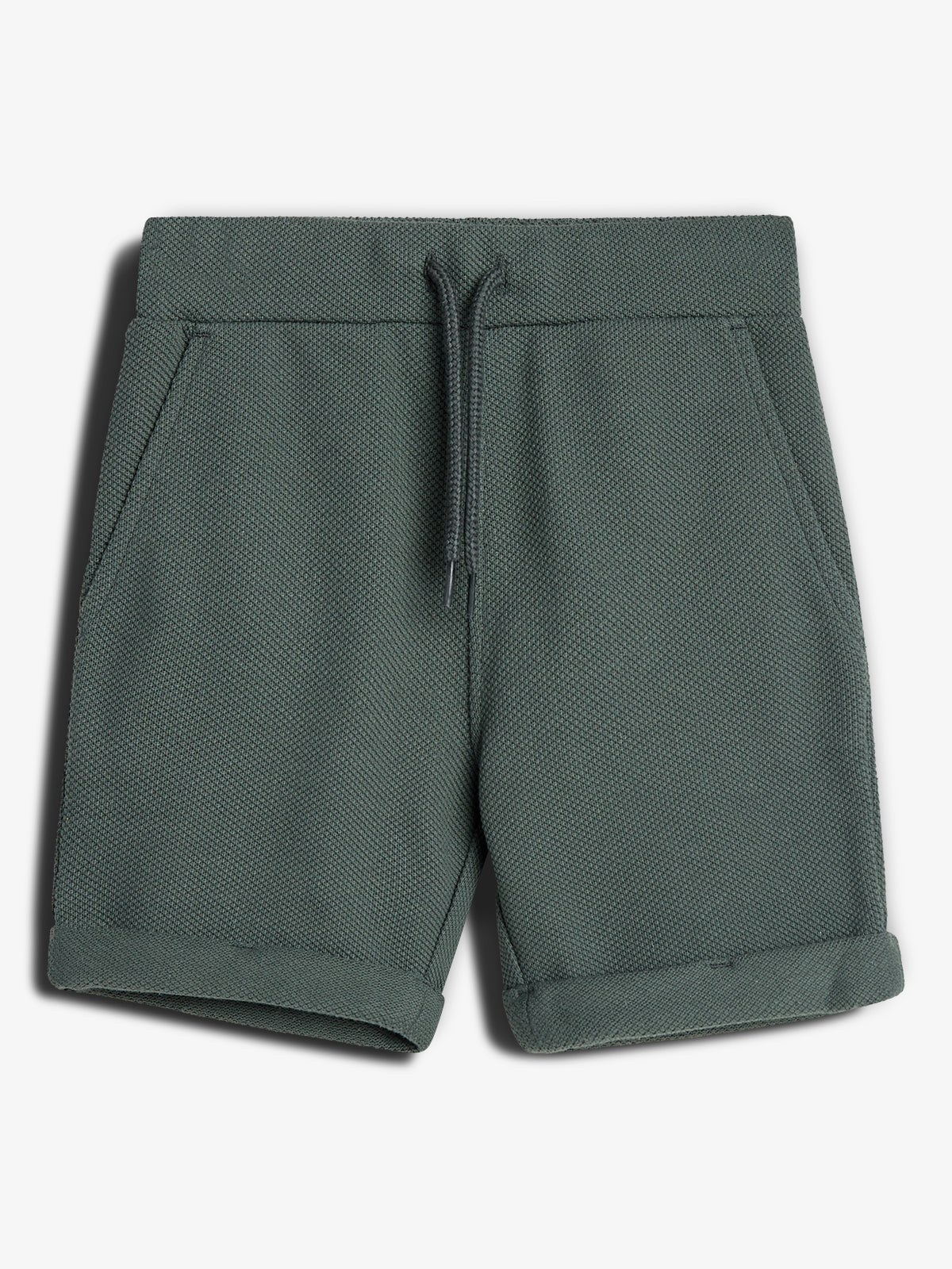 Grønne shorts med snøre i taljen, liggende fladt mod en hvid baggrund. Stoffet har en tekstureret overflade. Ingen tekst ses på billedet.