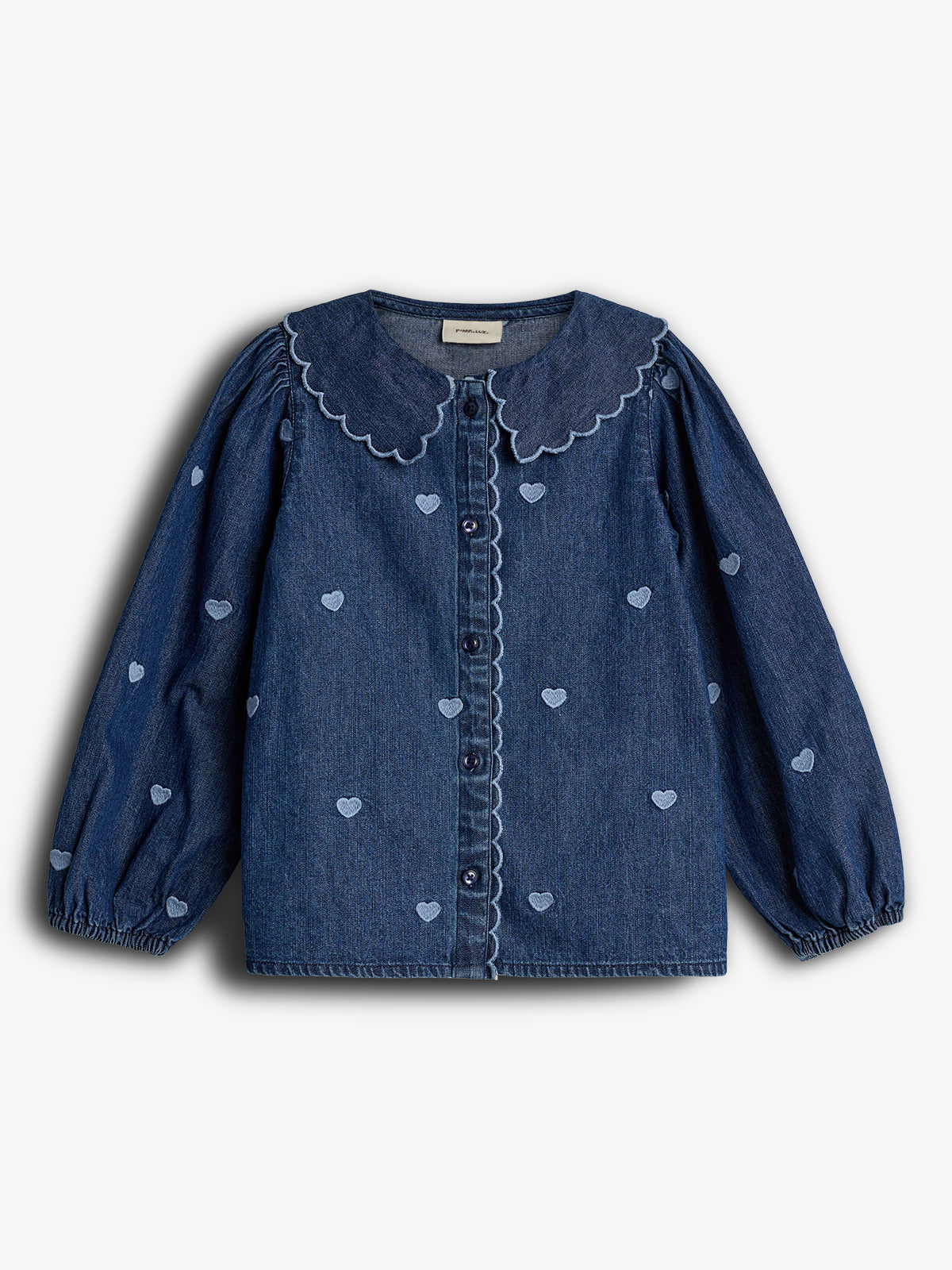 Bluse i denimstof med lange ærmer, rund krave, og knaplukning. Blusen har broderede hjerter og bølgede kanter. Den er præsenteret på hvid baggrund uden yderligere kontekst.