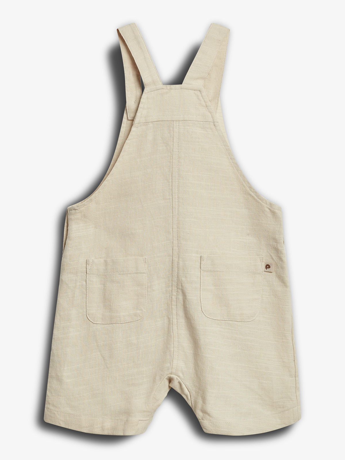 Børneoverall i beige stof med to frontlommer, placeret mod en hvid baggrund.