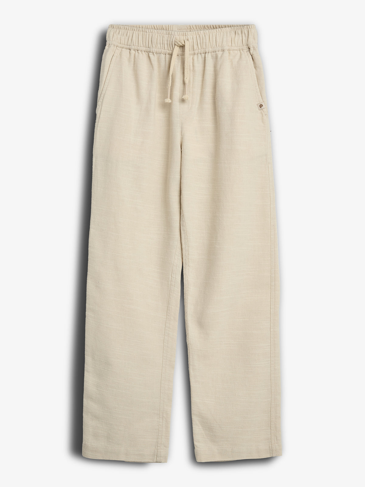 Beige bukser hænger frit med elastiklinning og snøre. Der er to sidelommer, og bukserne er i et enkelt design uden unødvendige detaljer. Baggrunden er ensfarvet hvid.