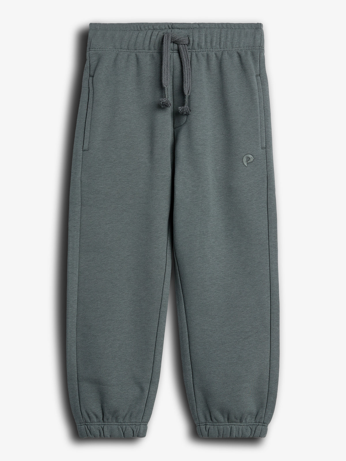 Grå joggingbukser med elastikbånd og snøre i taljen. De har sidelommer og en lille logodetalje. Baggrunden er enkel og hvid.