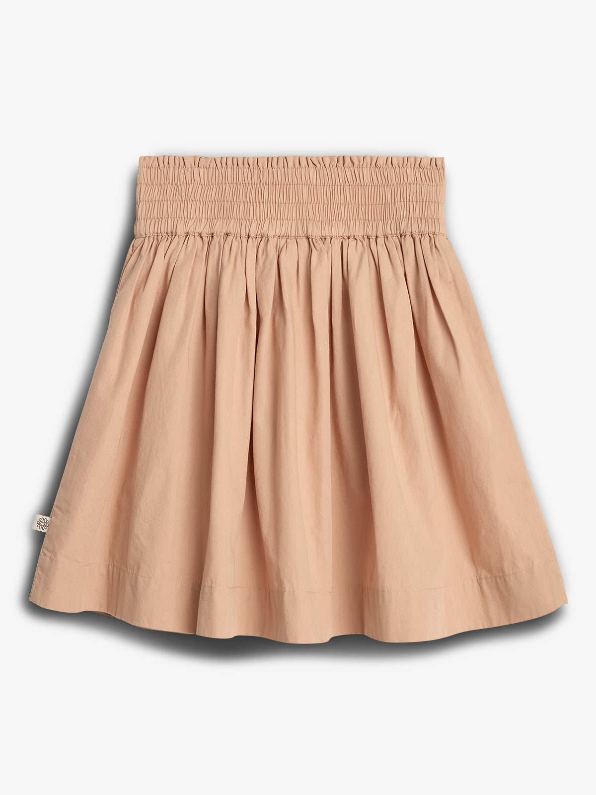 A beige, pleated skirt with an elastic, smocked waistband hangs against a plain white background, showcasing its simple, elegant design.