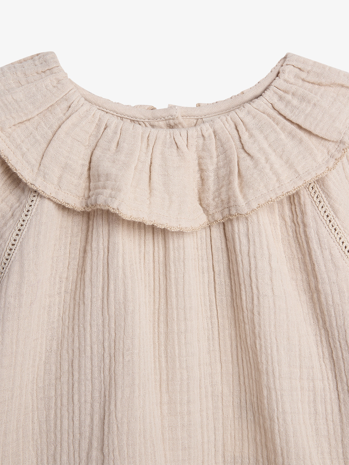 A beige, textured fabric with a frilled collar and vertical seams is displayed, suggesting a garment detail against a plain white background.