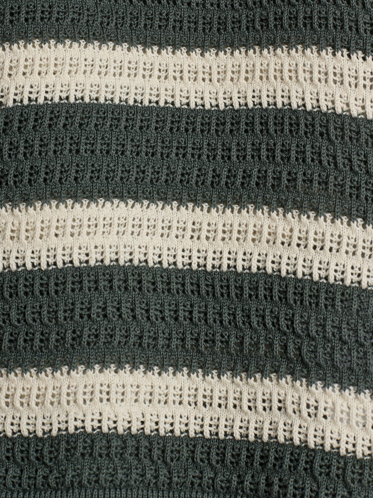 Textured fabric features alternating black and white horizontal stripes, with a waffle-like knit pattern. The fabric's texture creates a three-dimensional appearance, enhancing the contrast between the colors.