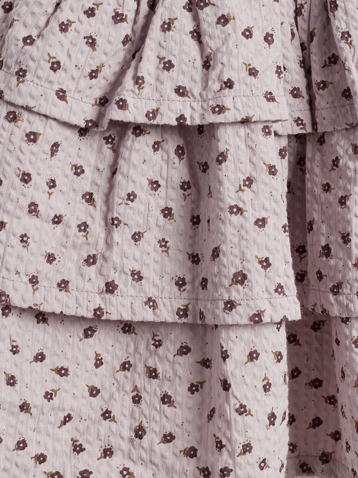Ruffled fabric with small burgundy floral prints; the material is slightly textured, layered, and folds in a cascading style, suggesting a dress or skirt.