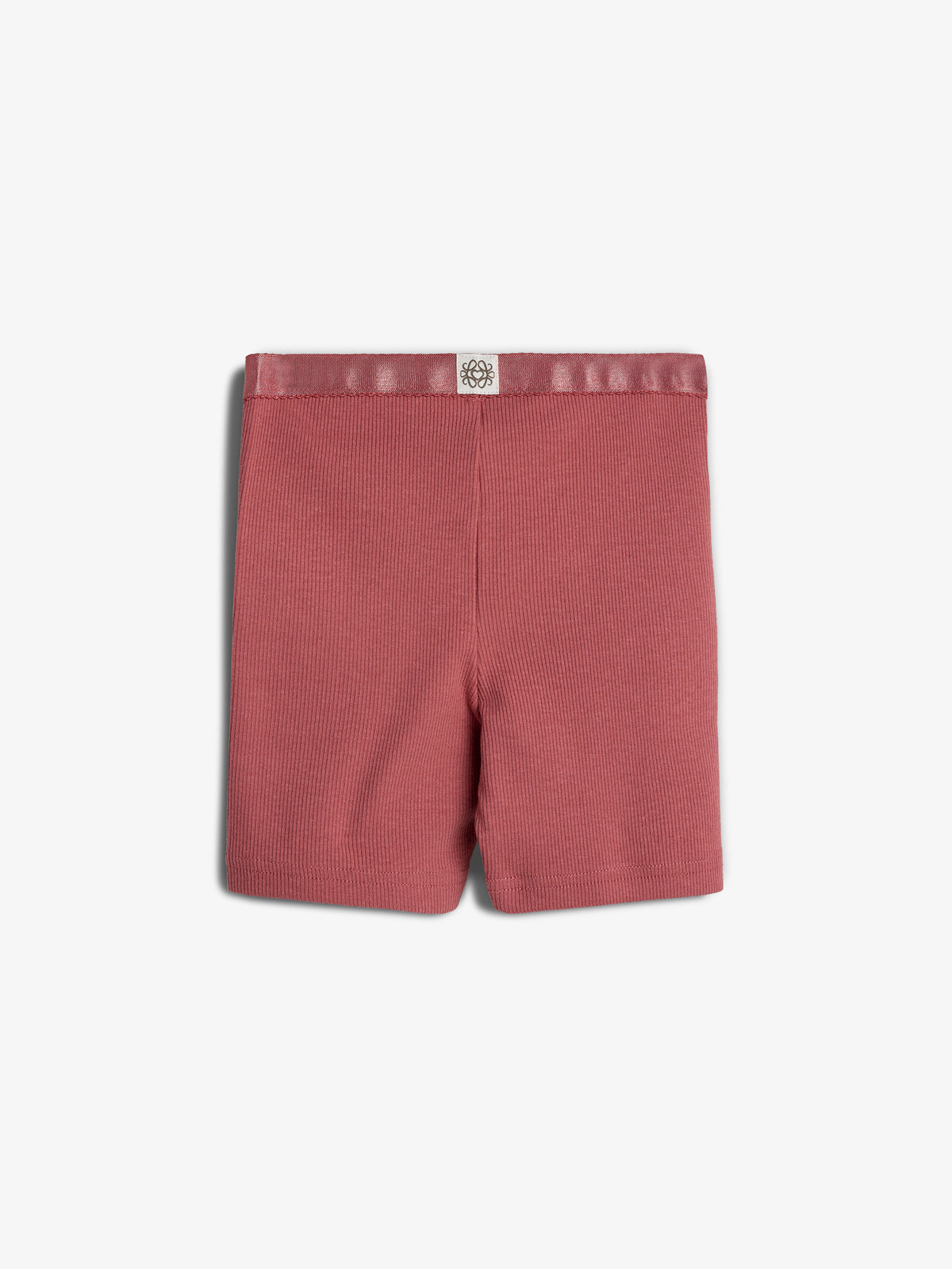 Røde shorts ligger fladt, med ribbet tekstur og en elastikbånd øverst, på en hvid baggrund. Over elastikken er der et lille, hvidt logo med et blomstermotiv.