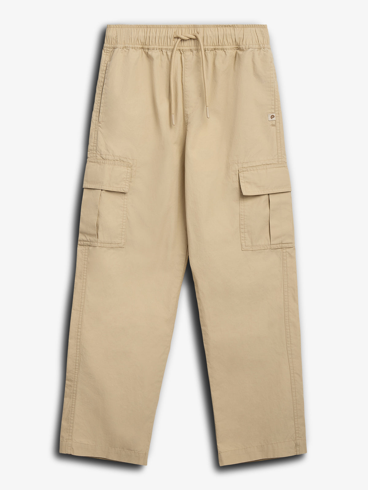 Bukser i beige farve, ligger fladt. Har elastisk talje og snøre, flere lommer, herunder to store cargolommer, fotograferet mod en ensfarvet baggrund.