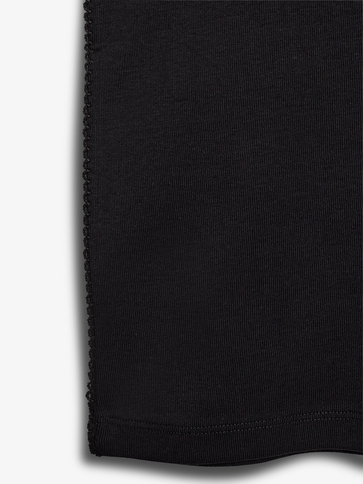 Sort stof med syninger langs kanterne, ligger fladt mod en lys baggrund. Syningerne er tætte og jævne, hvilket indikerer kvalitetsforarbejdning i et simpelt design.