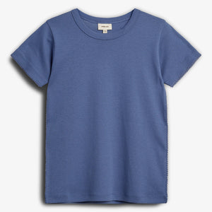 Blå T-shirt med korte ærmer hænger fladt. Der er en lille mærkat ved halsen med teksten "petit elin", størrelse "122". Baggrunden er enkel og hvid.