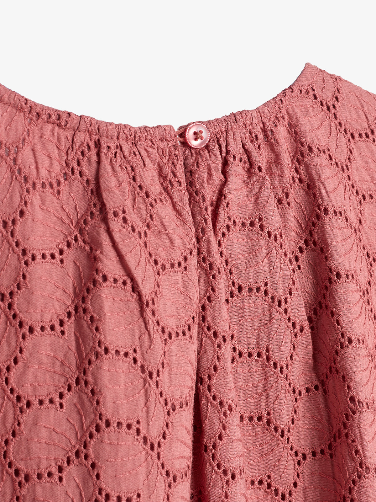A pink textured fabric with circular patterns is gathered at the top by a small, matching button, against a plain white background.