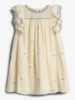 A cream-colored dress with ruffled sleeves is adorned with small, dark heart patterns and stylish embroidery. It hangs against a plain white background, displaying its elegant design and craftsmanship.