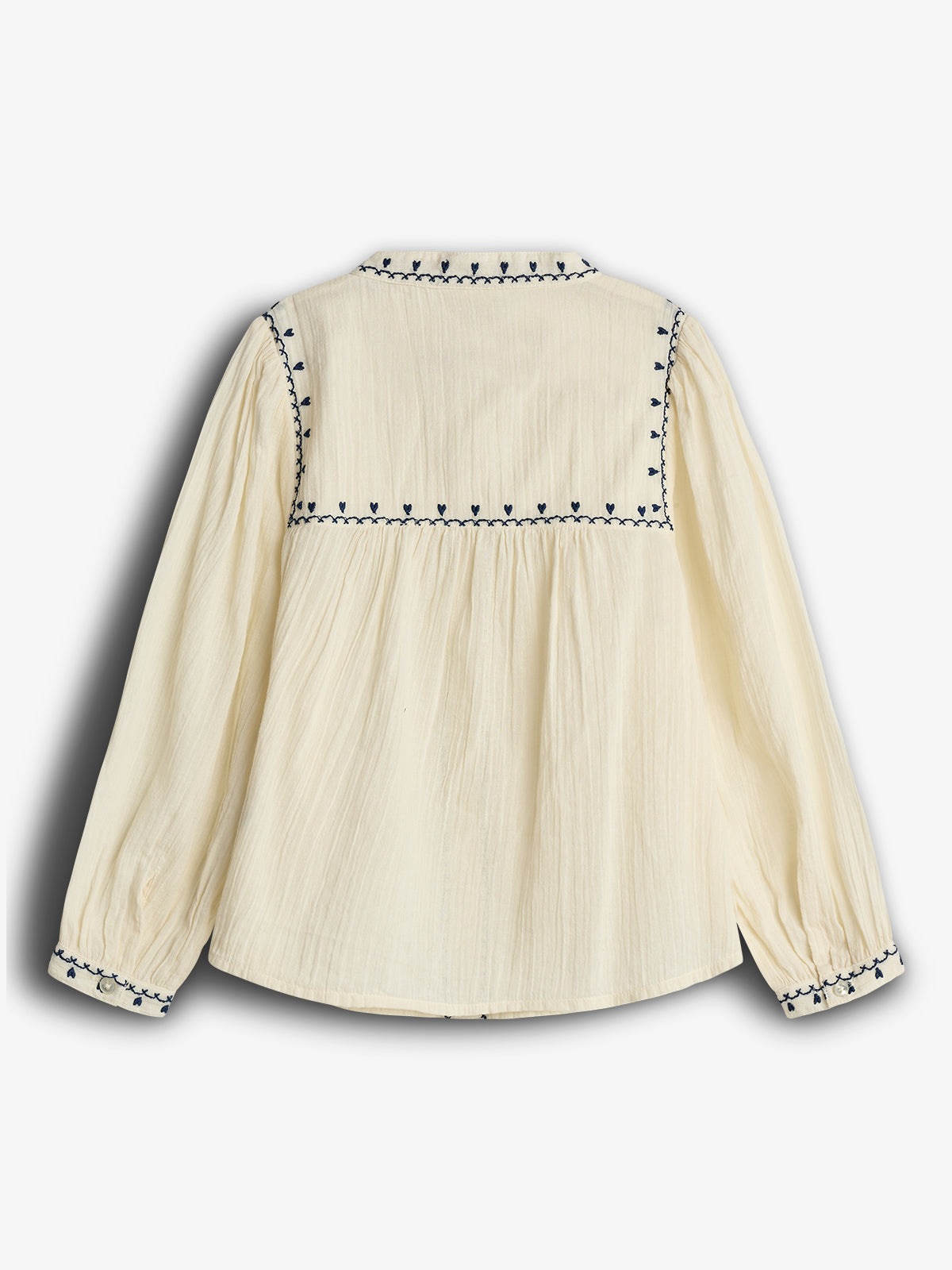 Cream-colored blouse with long sleeves features navy heart-shaped embroidery along the cuffs, shoulders, and upper back. The fabric appears lightweight and textured, set against a plain white background.