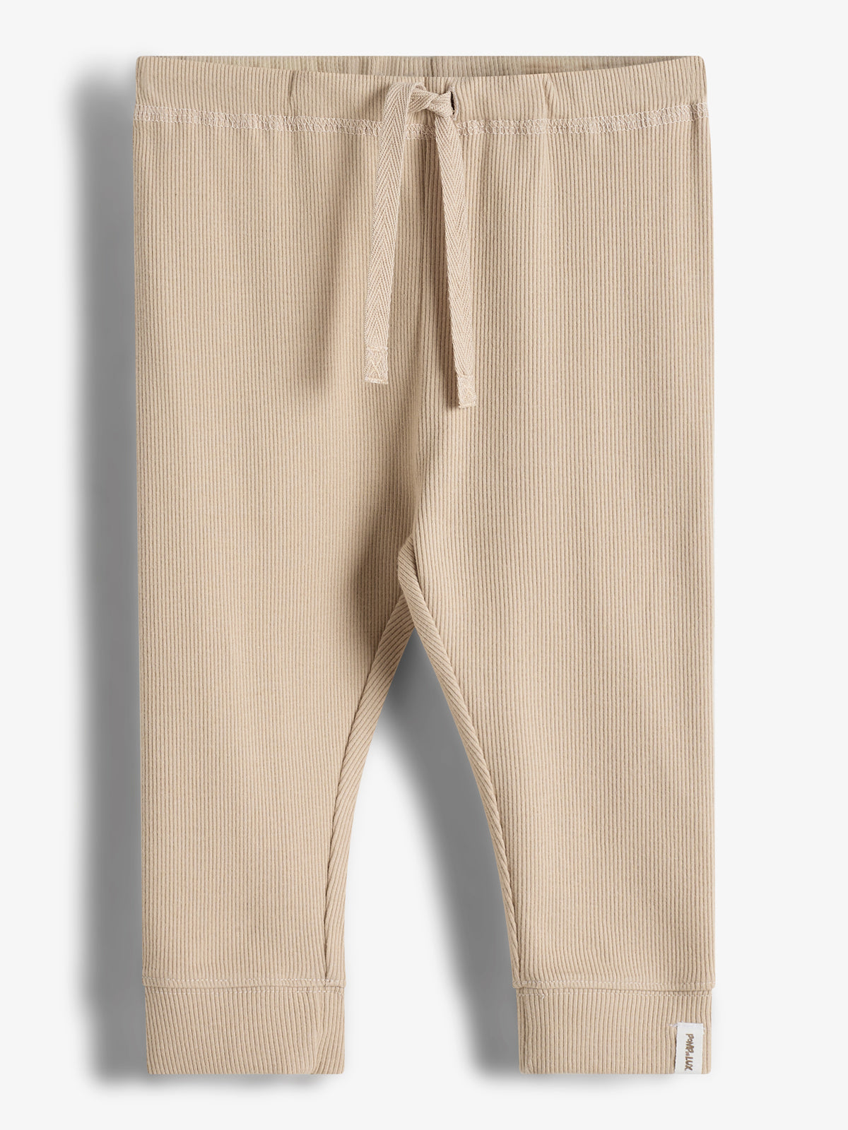 Beige ribbed-knit baby pants with a drawstring waist, displayed flat against a white background. A small tag at the hem reads "purebaby LUX."