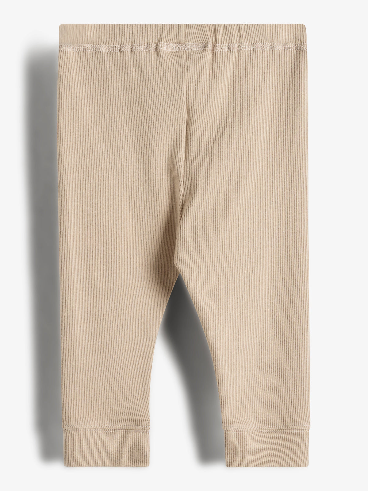 Beige ribbed leggings are laid flat with a visible elastic waistband, against a plain, light-background, highlighting their texture and simplicity.