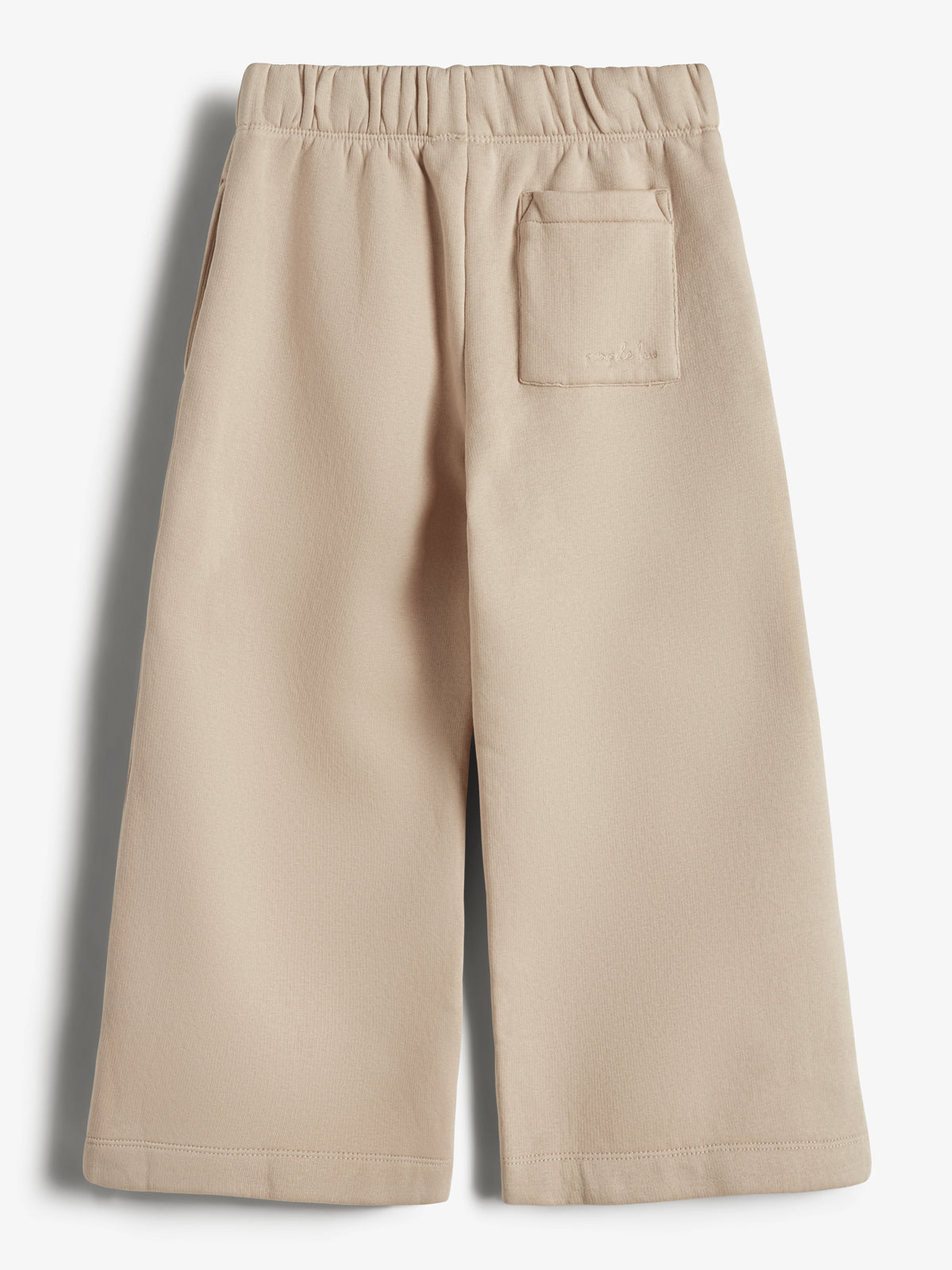 Beige bukser med bredt ben, elastisk talje og en baglomme. De hænger udenfor i en neutral baggrund. Skriften på lommen siger "PAARKO."