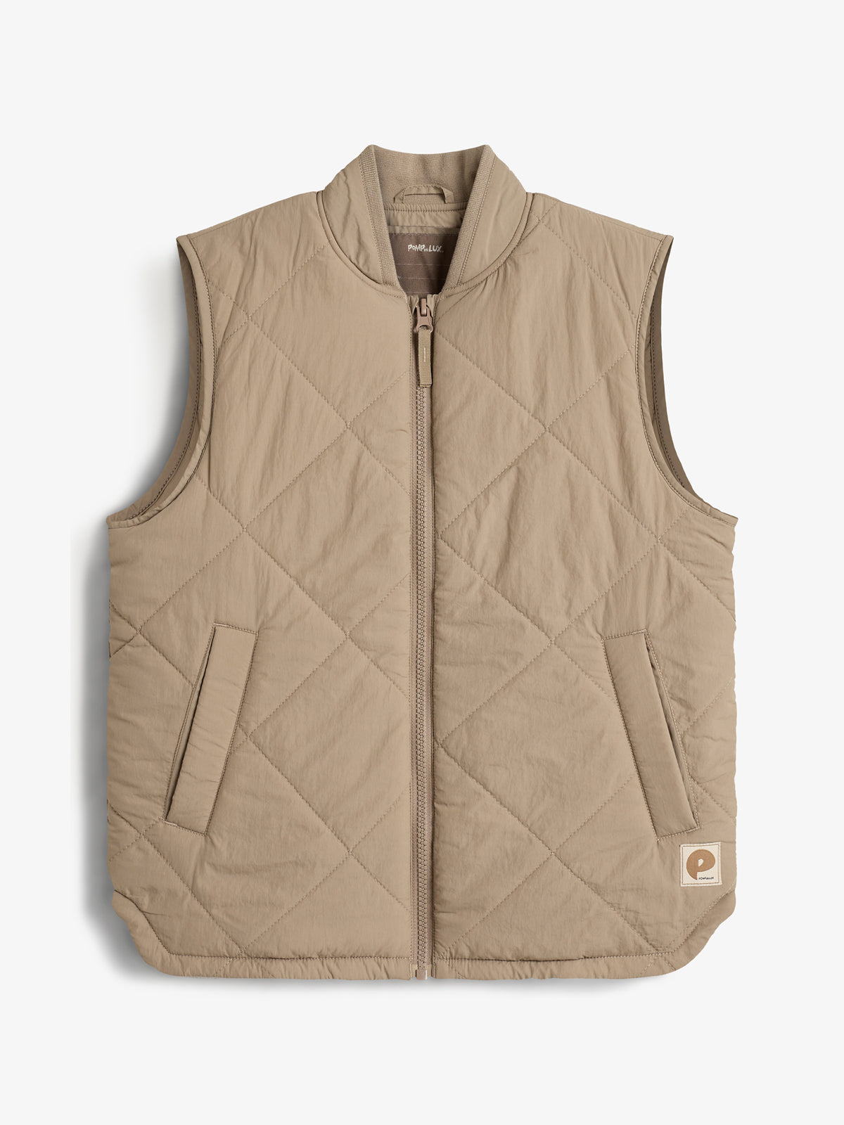 Beige quiltet vest med lynlås i midten og to sidelommer, placeret på en hvid baggrund. Vestens nederste højre hjørne har et mærkelogo. Tekst: "PAS NORMAL."