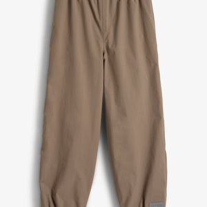 Bukser med elastisk talje og ben, der hviler fladt mod en lys baggrund. De er ensfarvede brune med en lille mærkat ved anklen med teksten "Polarn O. Pyret".